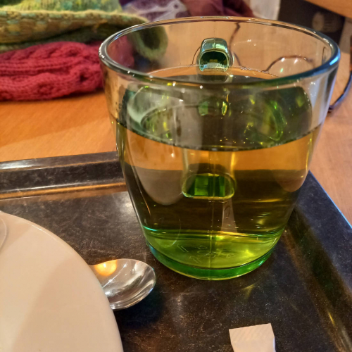 Grüne Tasse mit grünem Kräutertee.